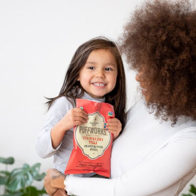 little girl and mom holding bag of strawberry PB&J puffs