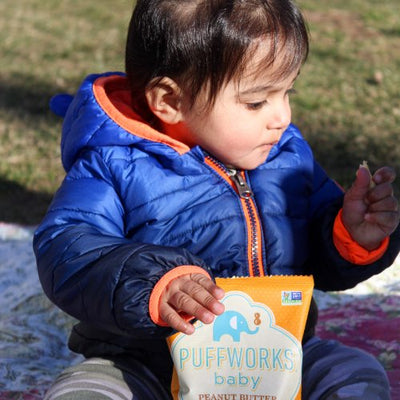 girl outside holding bag of Puffworks baby puffs