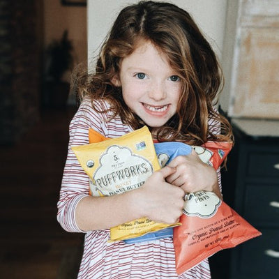 little girl holding Puffworks snack bags