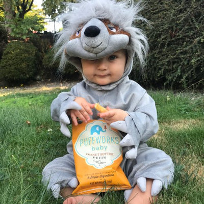 toddler in halloween costume eating Puffworks baby puffs